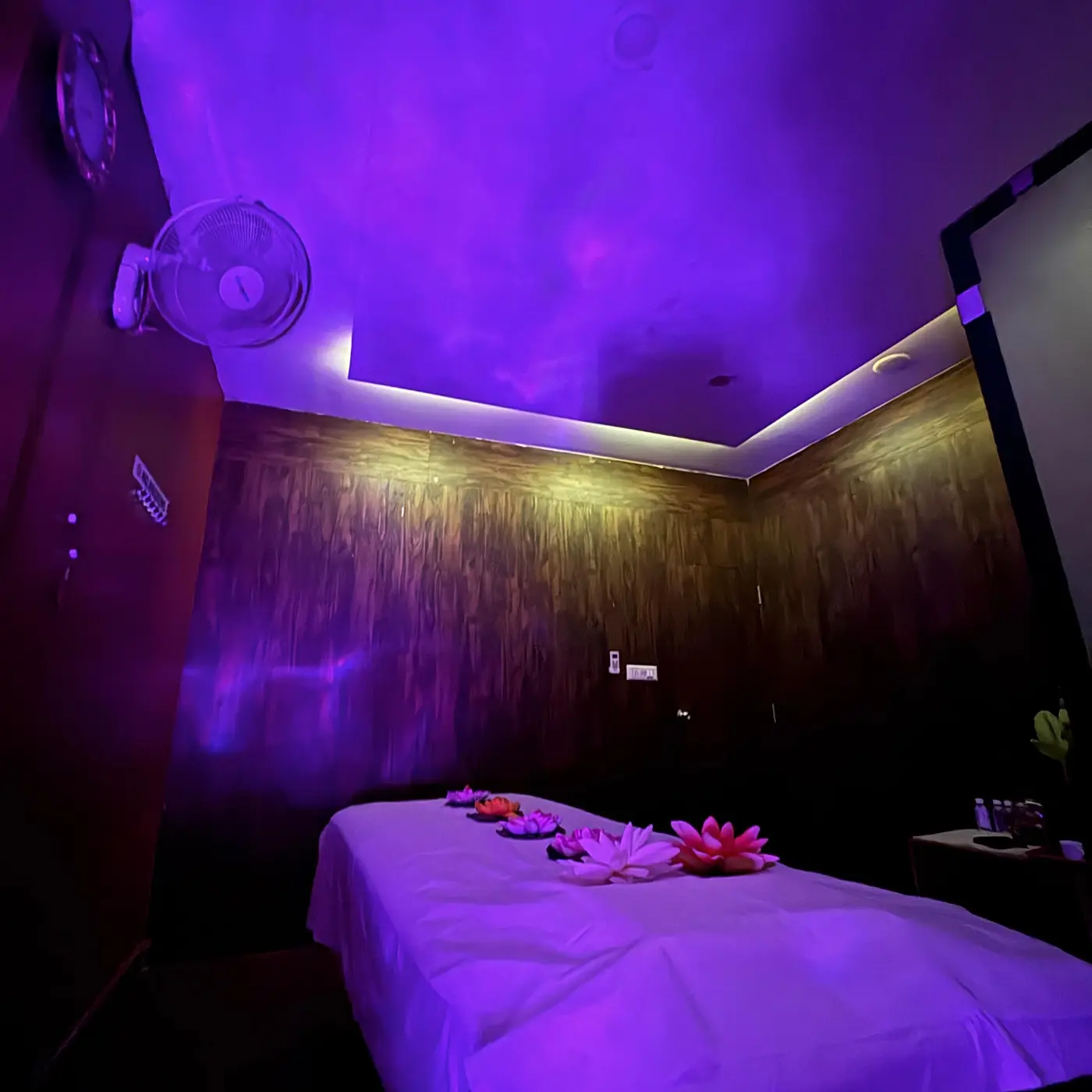 Wide view of a private massage suite with textured wood walls and cove lighting