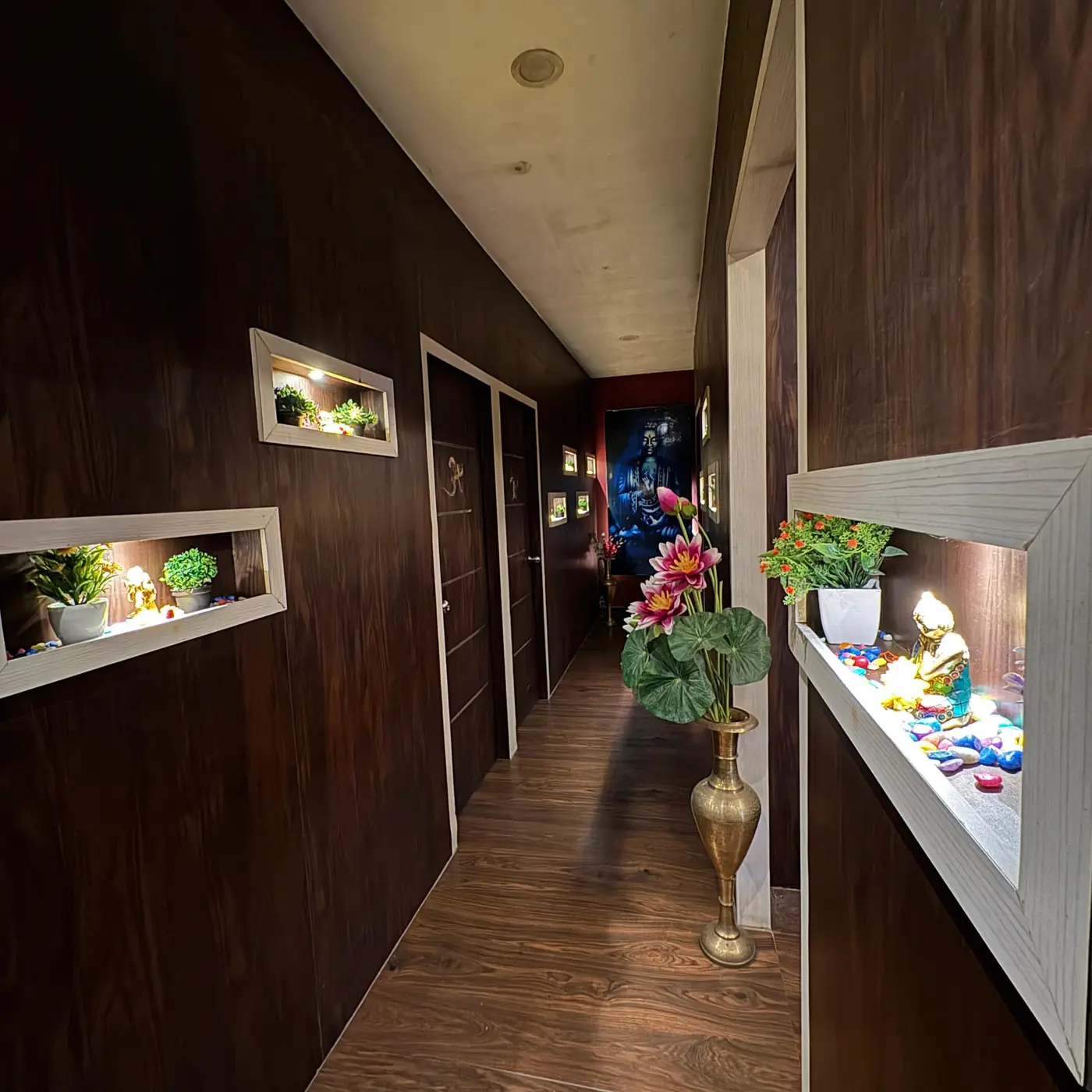 Spa corridor with brass vase, lotus flowers and lit display niches leading to treatment rooms
