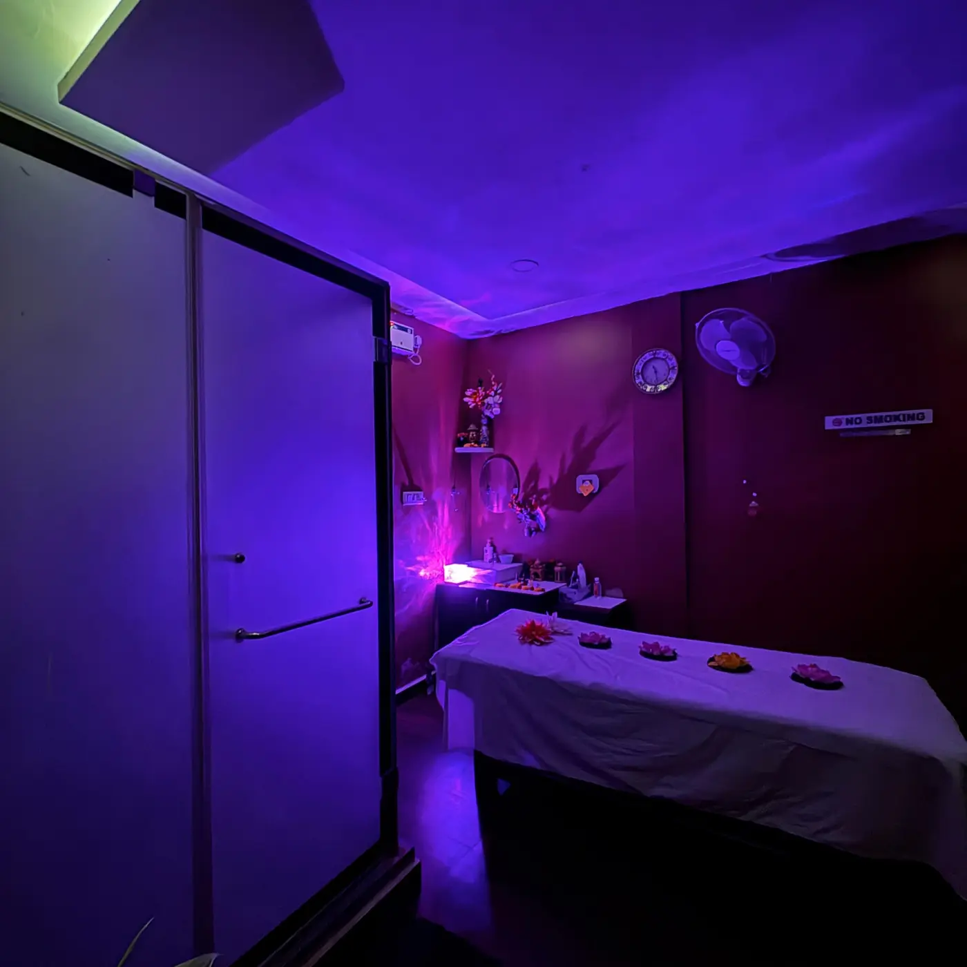 Massage suite with fresh linen, lotus decor and warm corner lighting